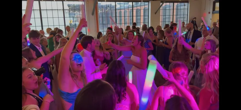 Bride celebrating with guests waving glow sticks
